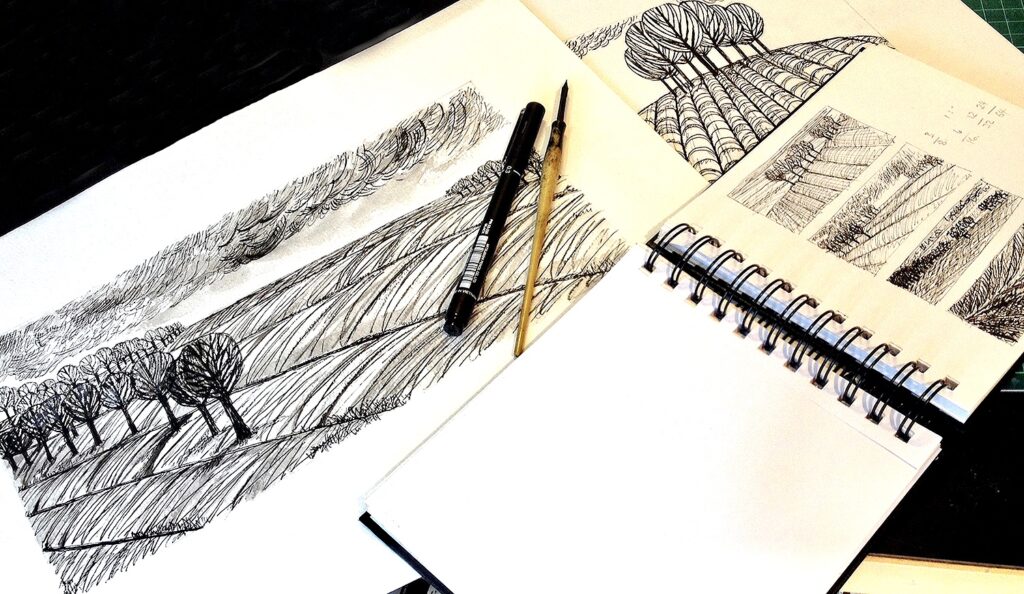 sketch books showing art and sketches in black and white of ploughed fields and trees