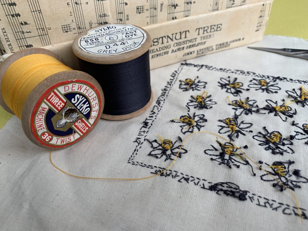 Worker Bees - Reverse of the work in progress - wooden reels of vintage threads in yellow and slate grey and the reverse of hand embroidered bees