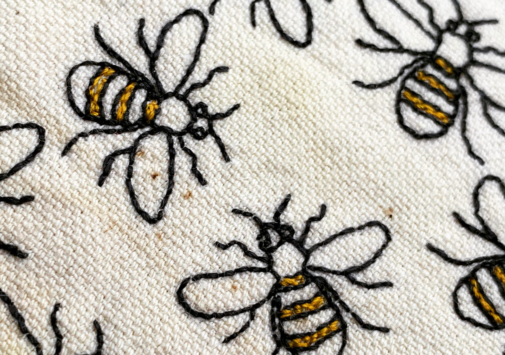 Close up of the hand embroidered bees in yellow and slate grey