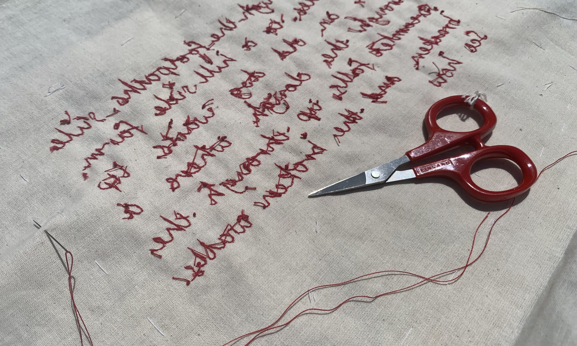 The reverse of the work showing red thread embroidery on cloth