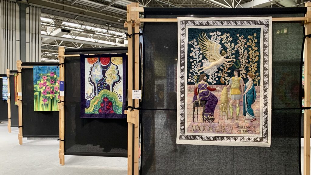 quilts hanging on quilt stands at the Festival of Quilts 2021