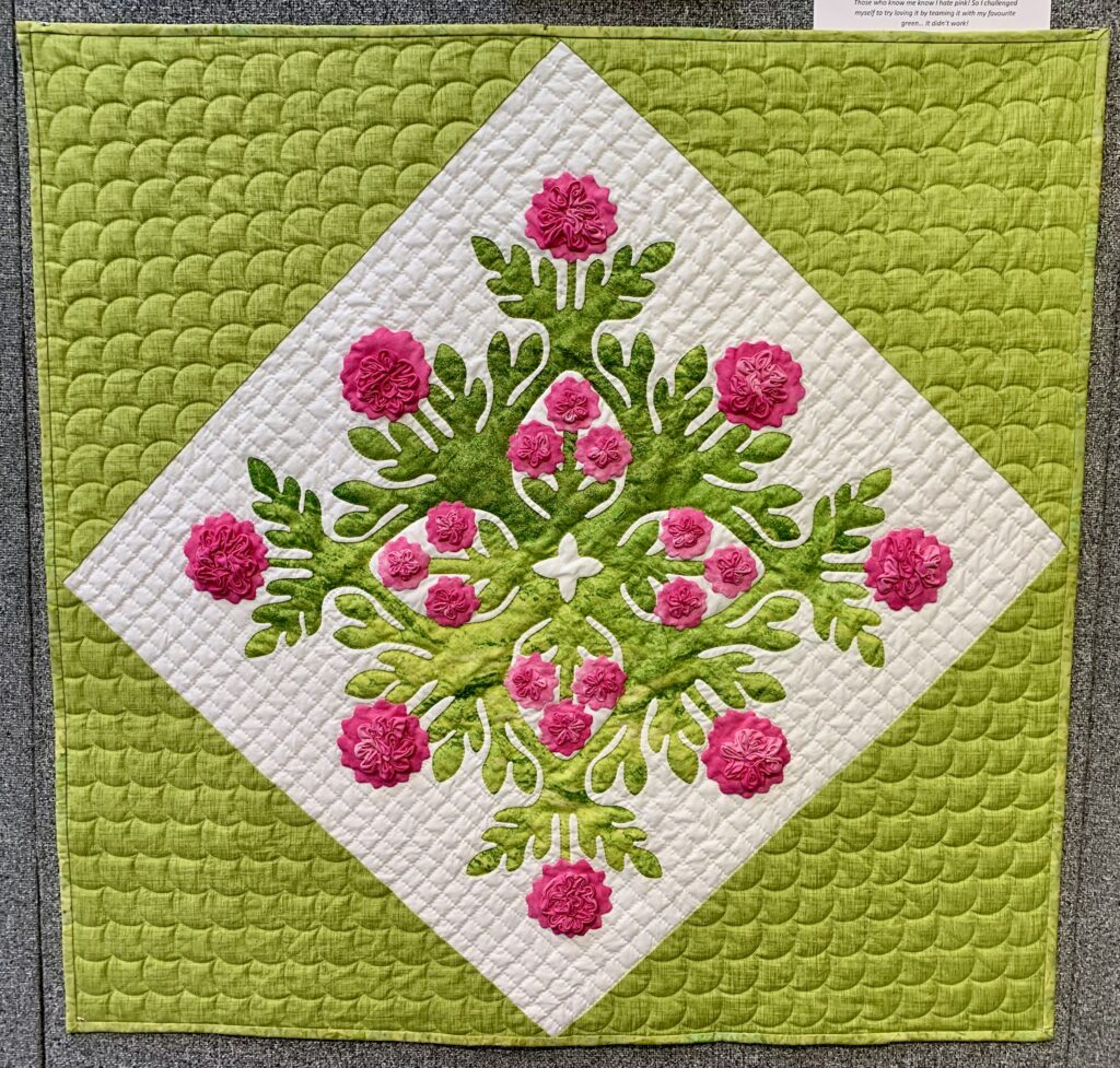 patchwork quilt. white square on point inside a lime green square. What square is filled with pink applique flowers and green leaves