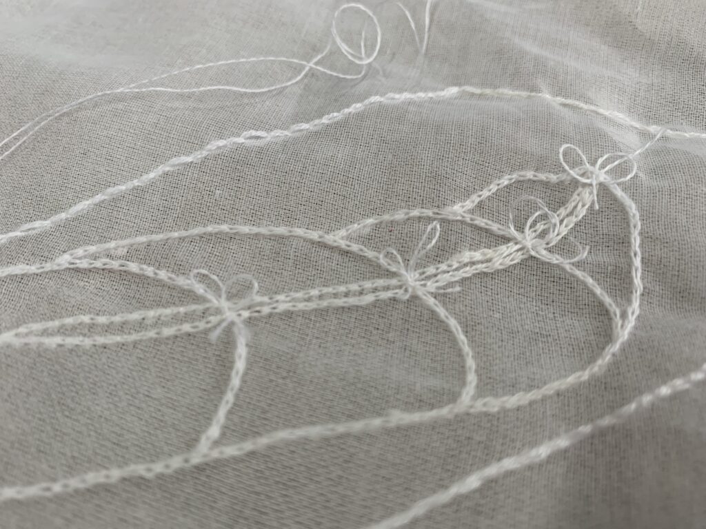 Collateral Project - hand embroidered white thread on silk organza - image of the outline of a body wrapped in cloth