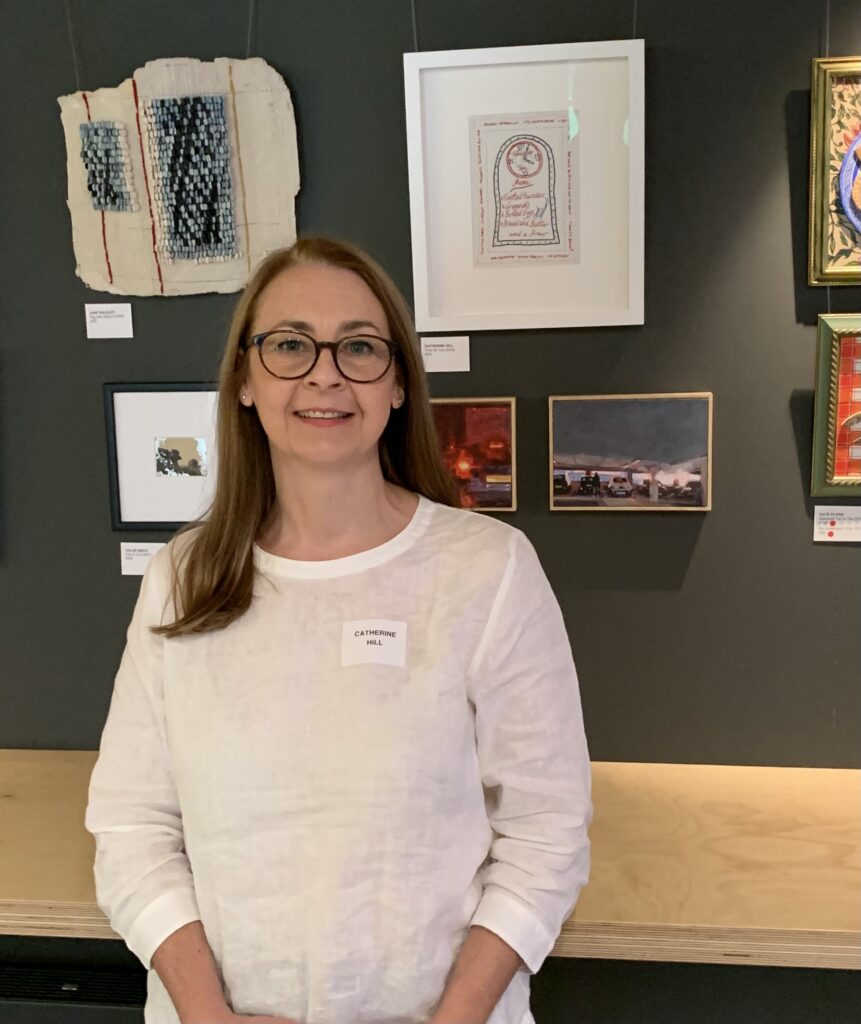 Catherine Hill standing next to her hand embroidered artwork