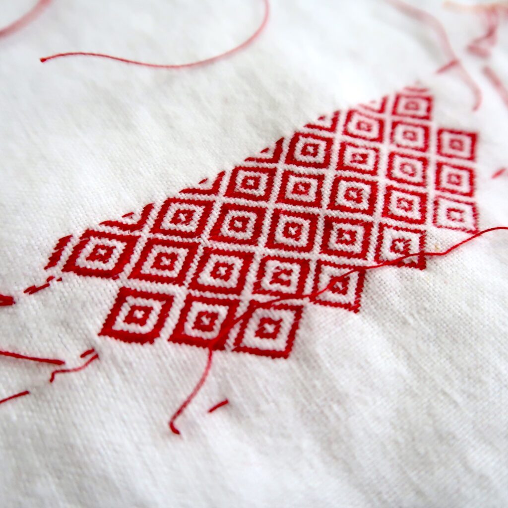 Darning Sampler - hand stitched red thread into a vintage white child's garment