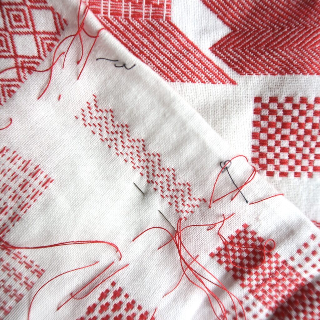 Darning Sampler - hand stitched red thread into a vintage white child's garment