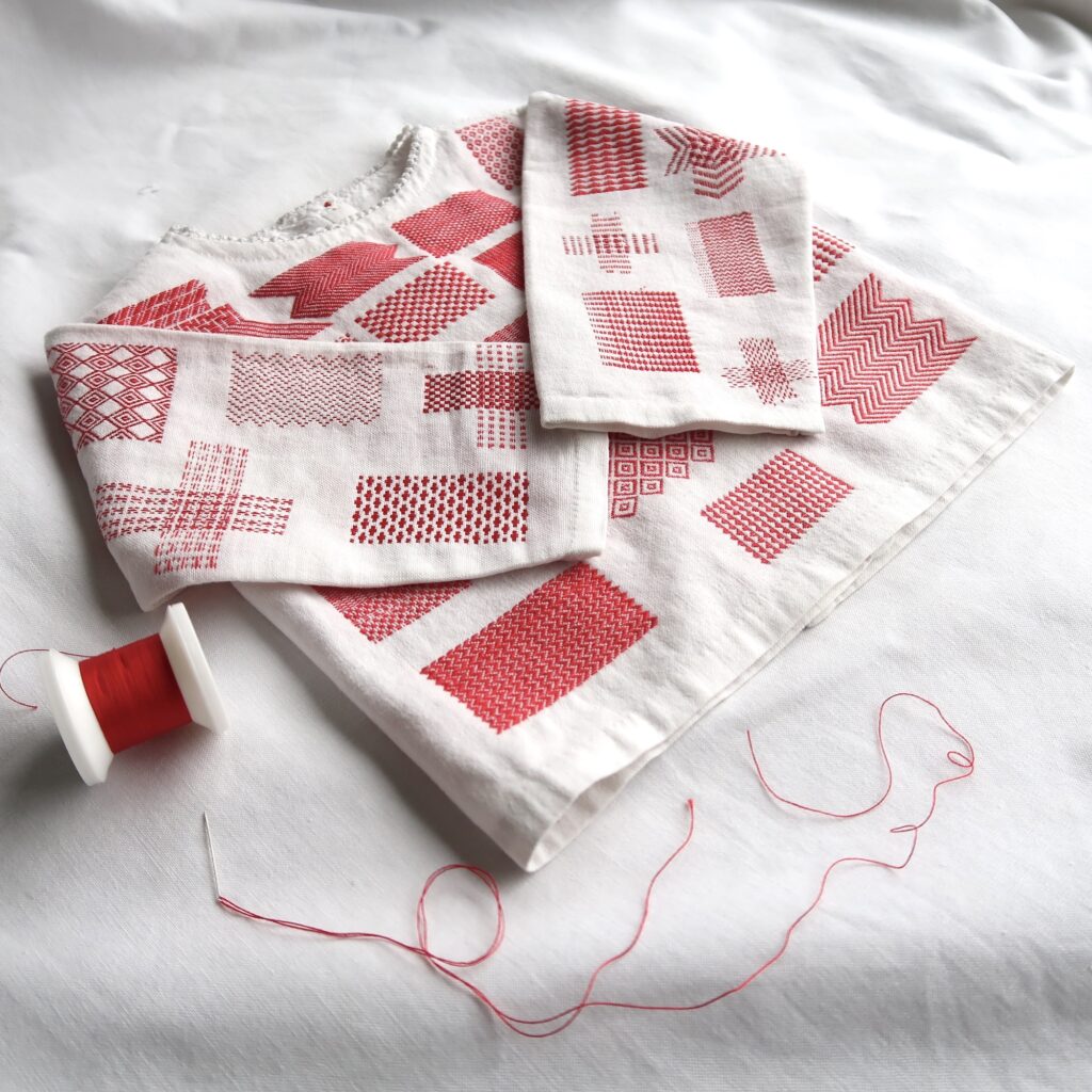 Darning Sampler - hand stitched red thread into a vintage white child's garment